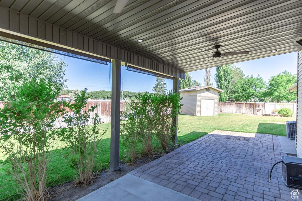 Fenced backyard with a patio, ceiling fan, and a shed