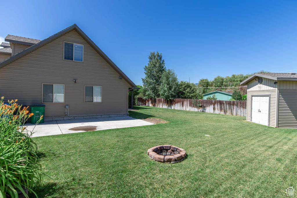 View of yard with a patio area, a storage shed, and an outdoor fire pit
