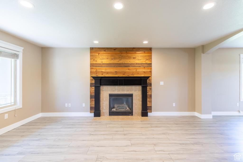 Unfurnished living room featuring recessed lighting, light wood finished floors, and a tile fireplace