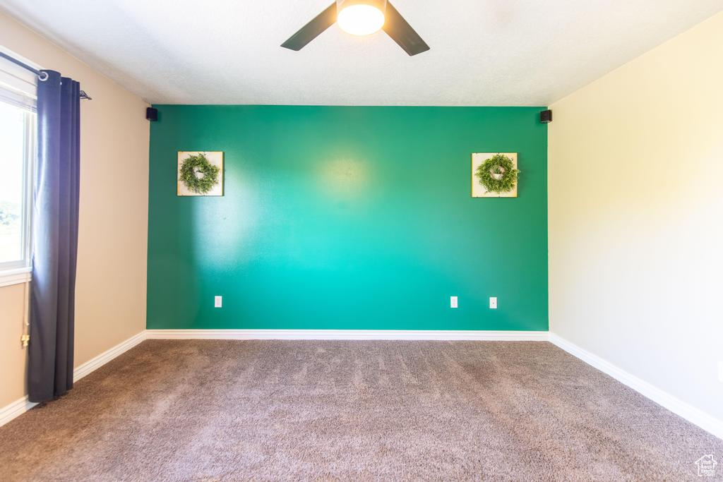Carpeted empty room featuring a ceiling fan and baseboards