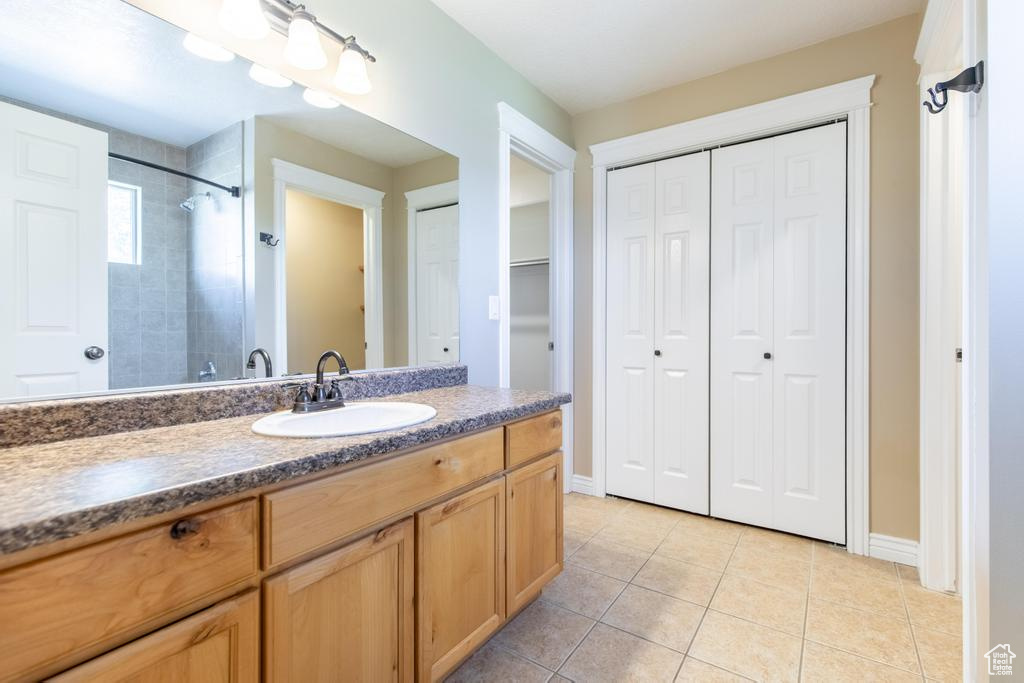 Full bath featuring a closet, vanity, a shower, and tile patterned flooring
