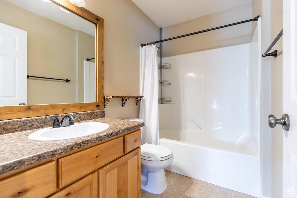 Bathroom with vanity, shower / tub combo with curtain, and tile patterned flooring