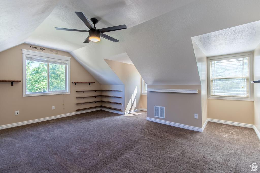 Additional living space featuring carpet flooring, a textured ceiling, lofted ceiling, and a ceiling fan
