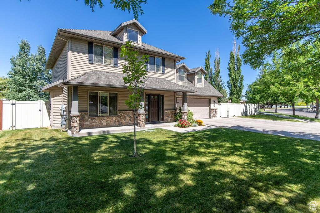 View of front of home with concrete driveway, a gate, a porch, an attached garage, and stone siding
