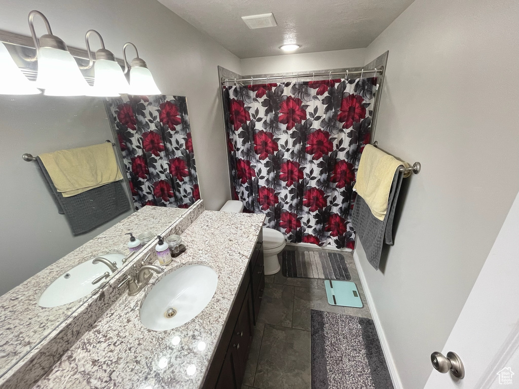 Full bath with vanity, stone tile flooring, and a shower with curtain