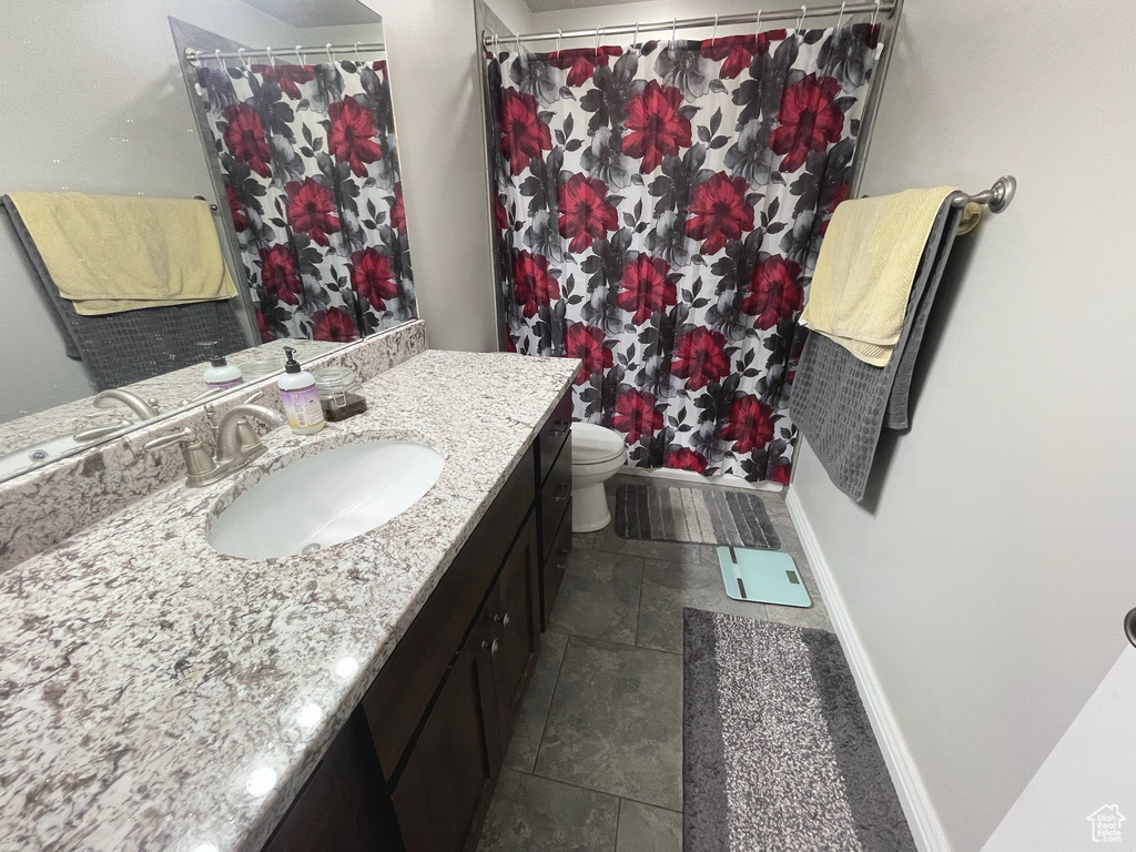 Bathroom with stone tile flooring, vanity, and a shower with shower curtain