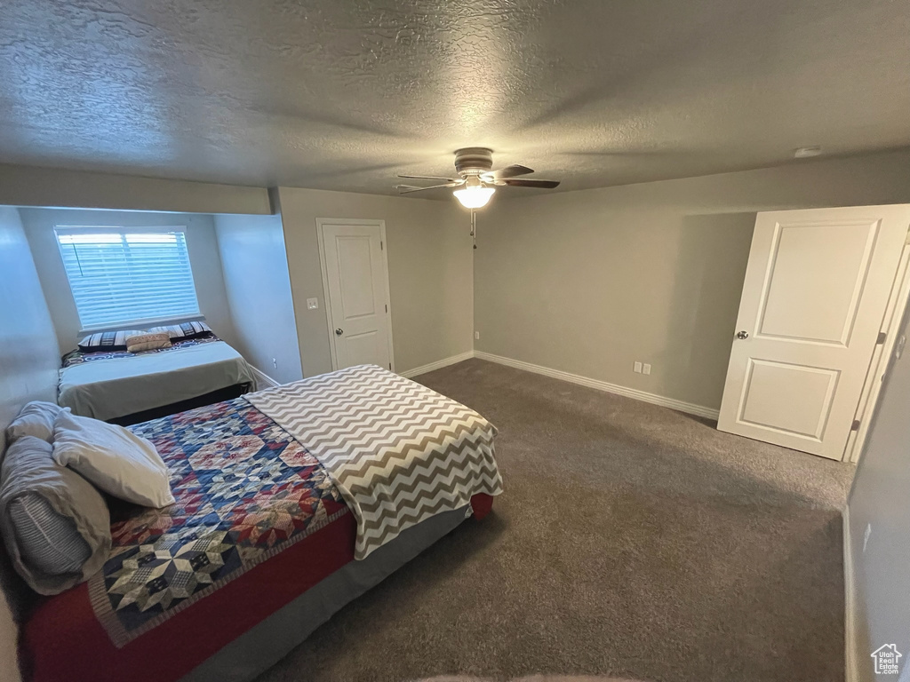 Bedroom featuring dark carpet, a textured ceiling, and ceiling fan