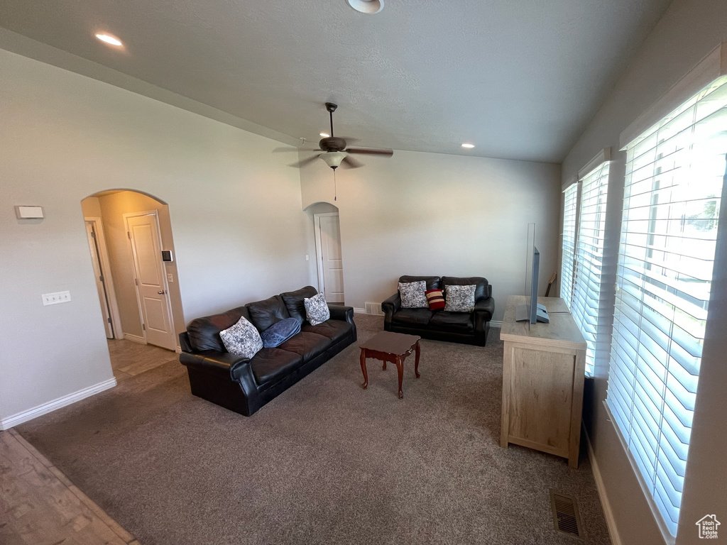 Carpeted living area with arched walkways, ceiling fan, and recessed lighting