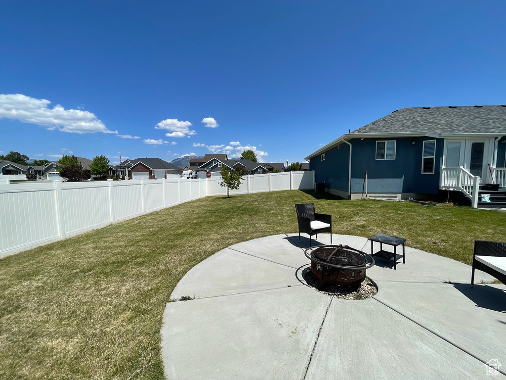 Fenced backyard featuring an outdoor fire pit, a patio, and a residential view