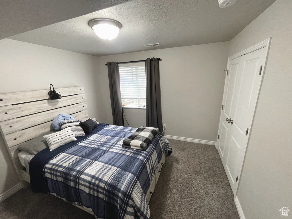 Carpeted bedroom featuring baseboards and a textured ceiling