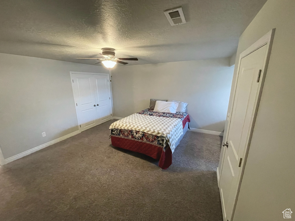 Bedroom with carpet floors, a textured ceiling, and a ceiling fan