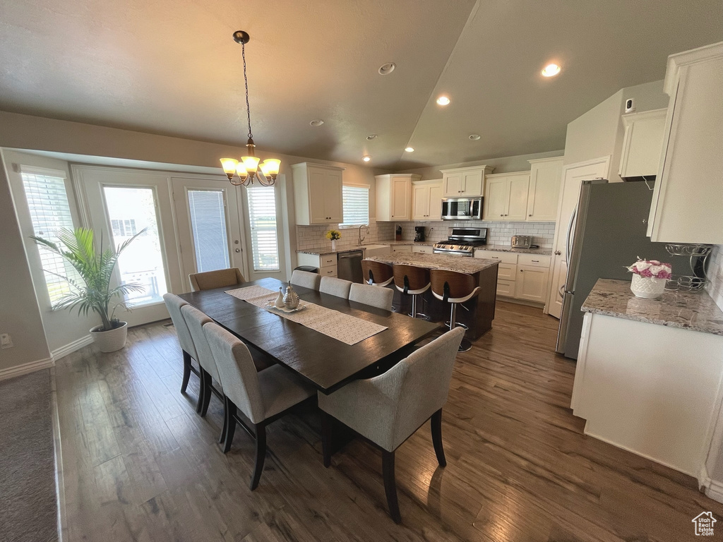 Dining space featuring a chandelier, dark wood finished floors, recessed lighting, and lofted ceiling