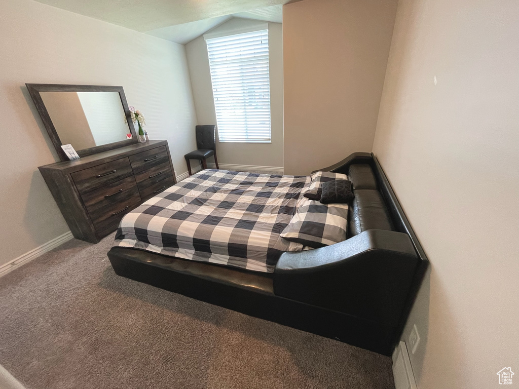 Carpeted bedroom featuring vaulted ceiling and baseboards