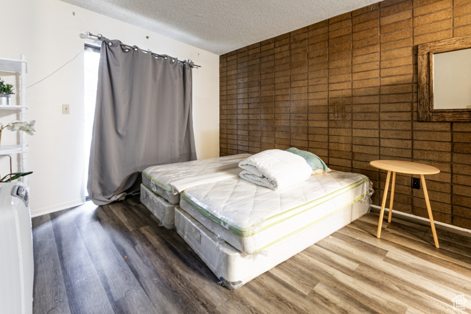 Bedroom with a textured ceiling and wood finished floors