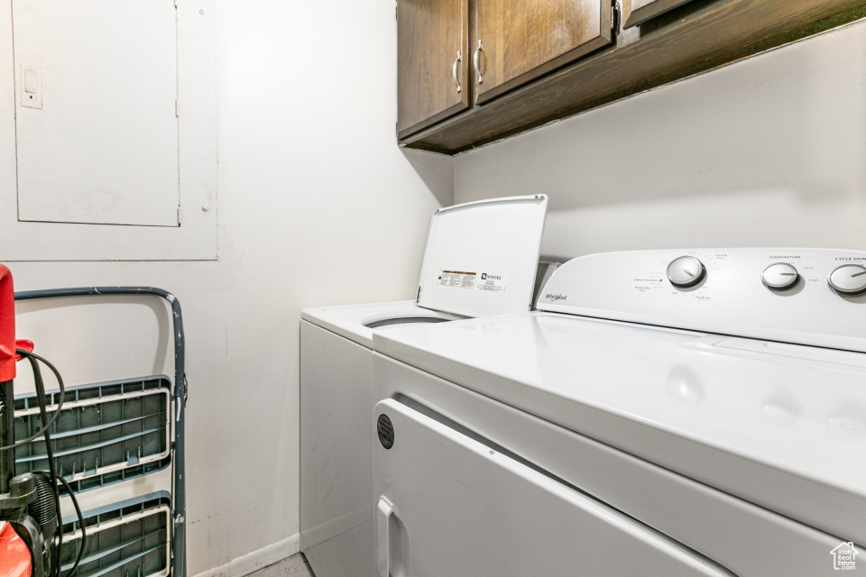 Laundry room featuring cabinet space, washer and dryer, and electric panel