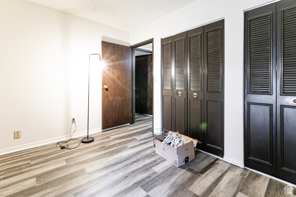 Unfurnished bedroom featuring light wood-type flooring, multiple closets, and a textured ceiling