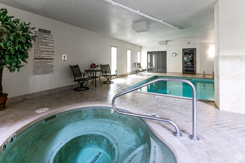 Indoor community pool featuring a hot tub