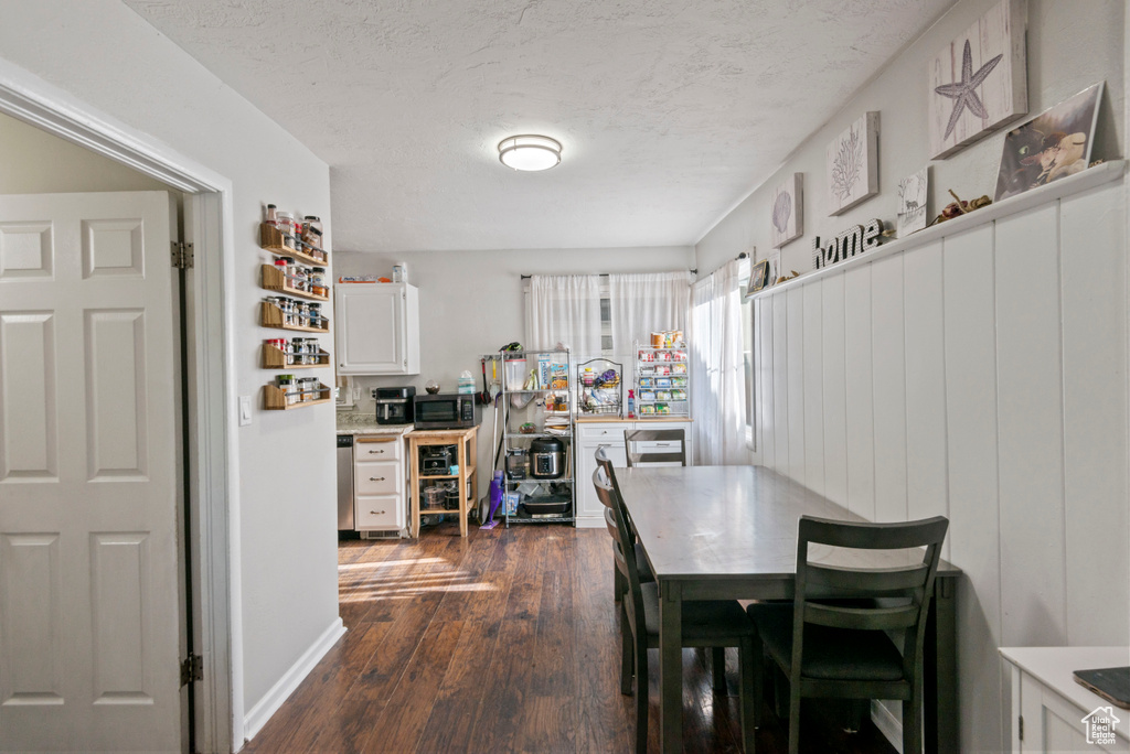 Dining area with dark wood-type flooring and a textured ceiling