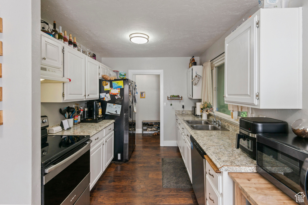 Kitchen with appliances with stainless steel finishes, under cabinet range hood, light countertops, dark wood-style floors, and a textured ceiling
