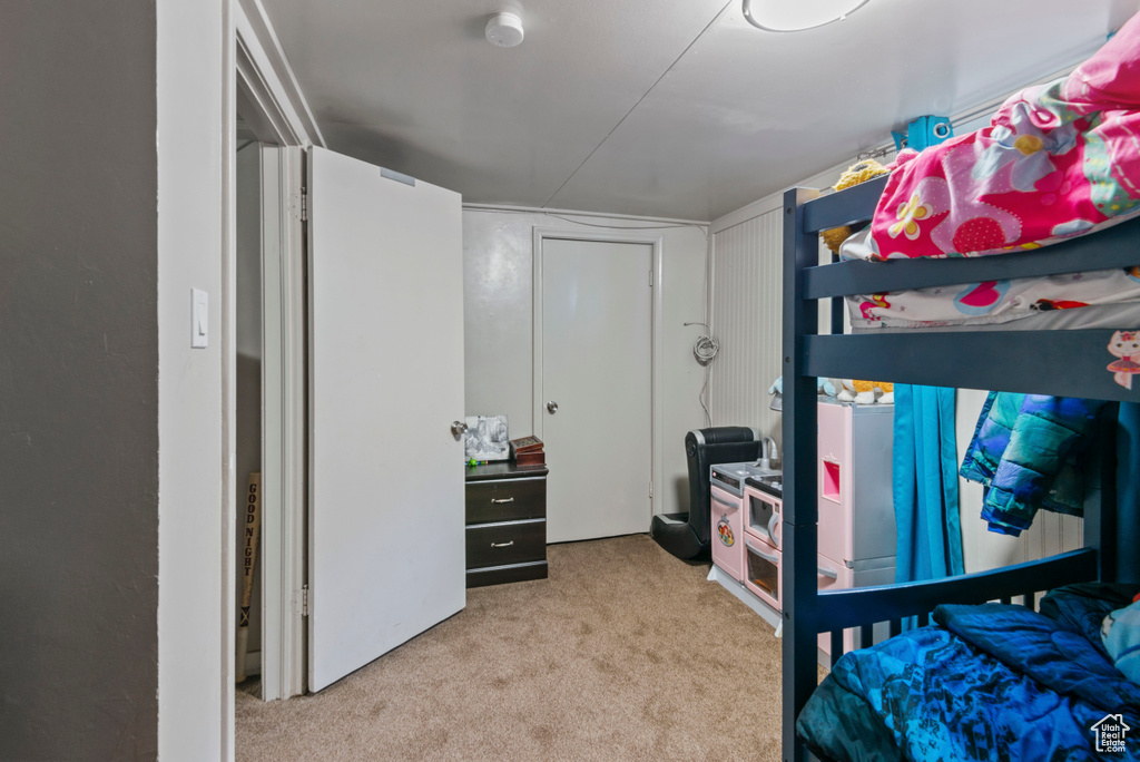 Bedroom with light colored carpet and freestanding refrigerator