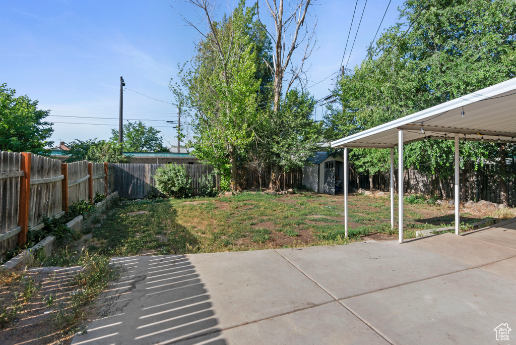 Fenced backyard featuring a patio area and a storage unit