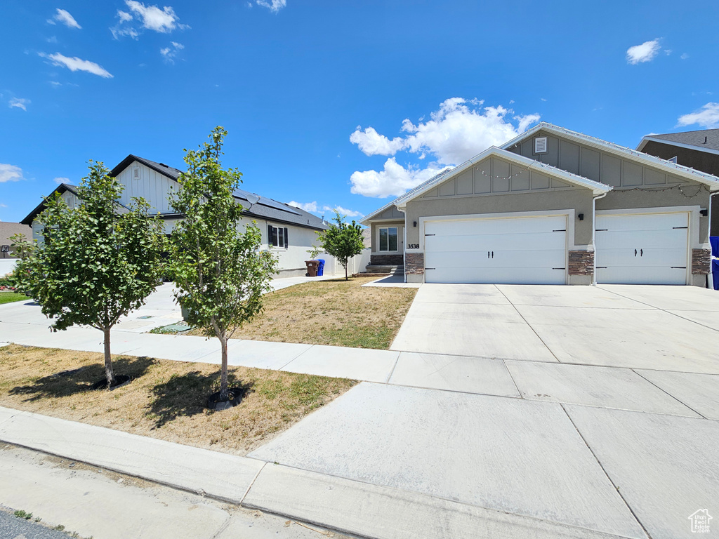 View of front of property featuring board and batten siding, an attached garage, and driveway