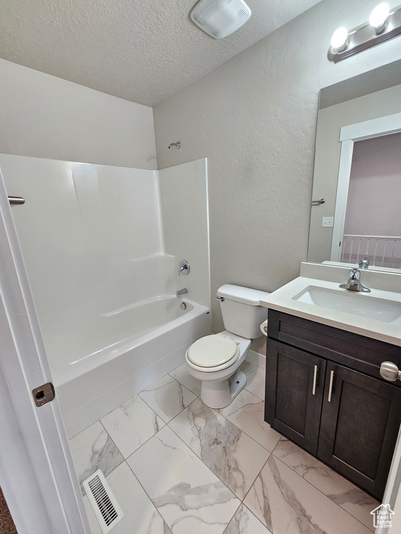 Bathroom featuring bathing tub / shower combination, vanity, a textured ceiling, marble look tiles, and a textured wall