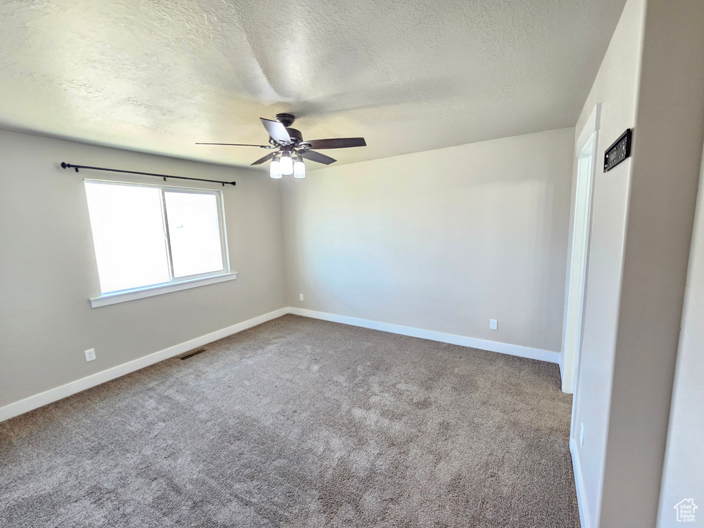 Carpeted spare room with a textured ceiling and ceiling fan