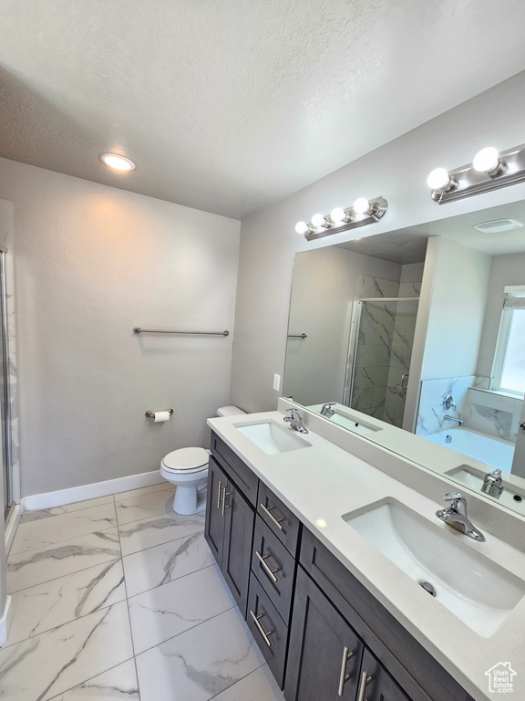 Bathroom featuring a stall shower, double vanity, marble finish floors, a garden tub, and a textured ceiling