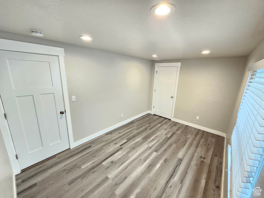 Unfurnished room with a smoke detector, light wood finished floors, and recessed lighting