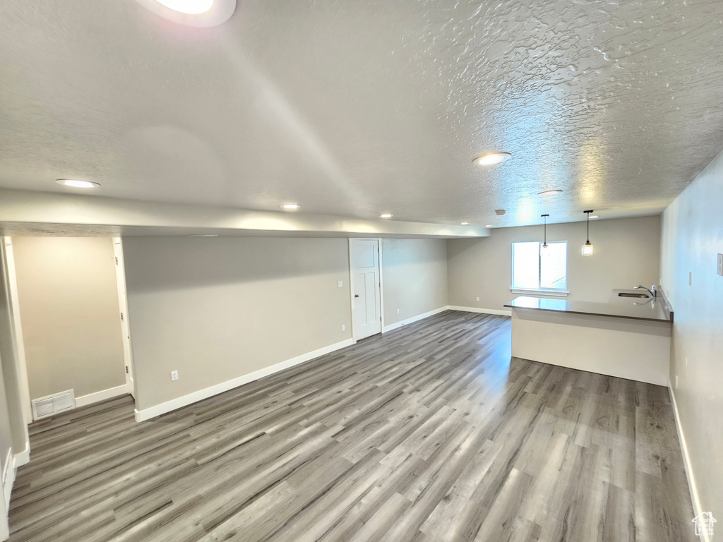 Basement with wood finished floors, recessed lighting, and a textured ceiling