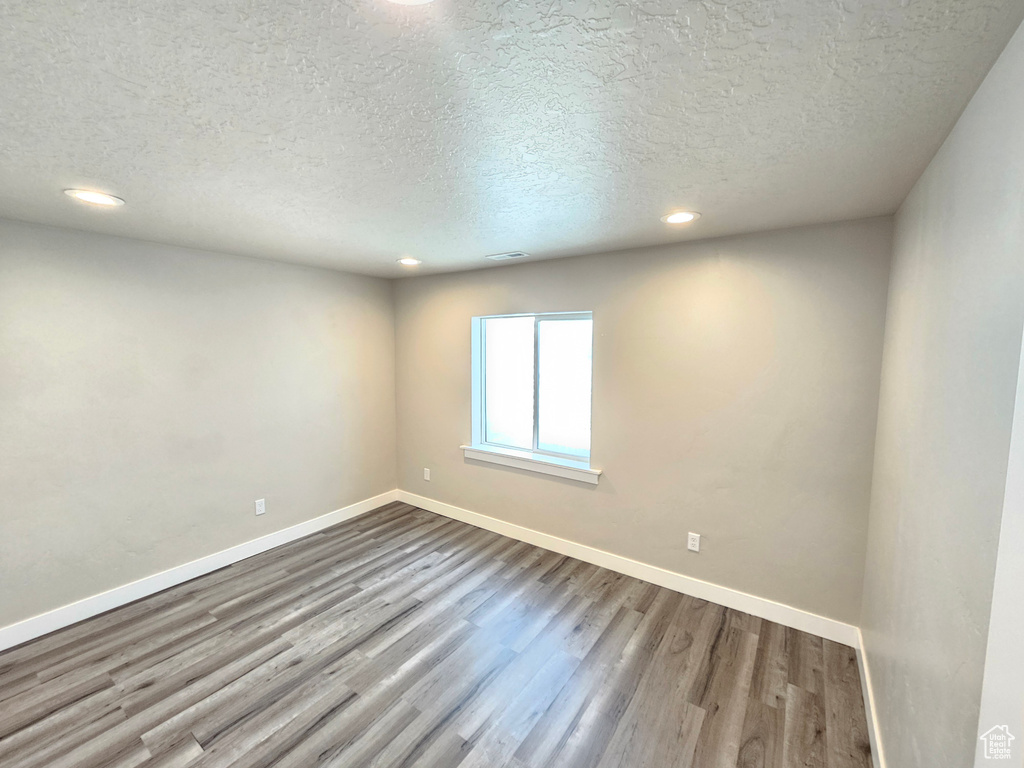 Unfurnished room featuring a textured ceiling, dark wood-style flooring, and recessed lighting