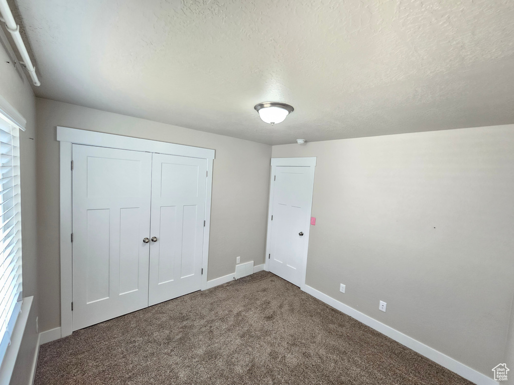 Unfurnished bedroom with a textured ceiling, carpet, and a closet