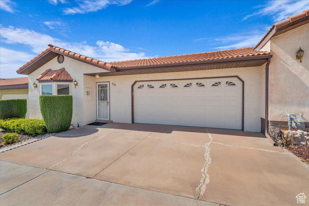 Mediterranean / spanish house with driveway, an attached garage, stucco siding, and a tiled roof