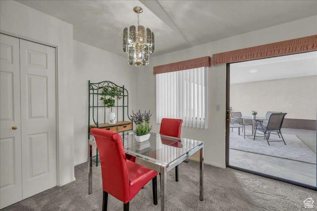 Carpeted dining room with a chandelier and baseboards