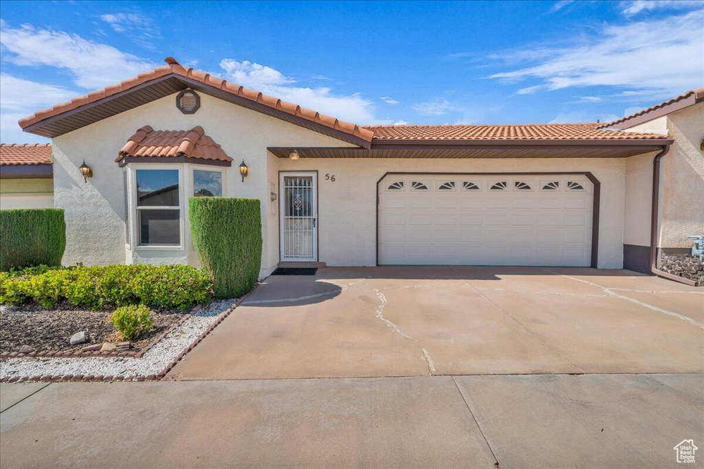 Mediterranean / spanish house featuring driveway, an attached garage, stucco siding, and a tiled roof