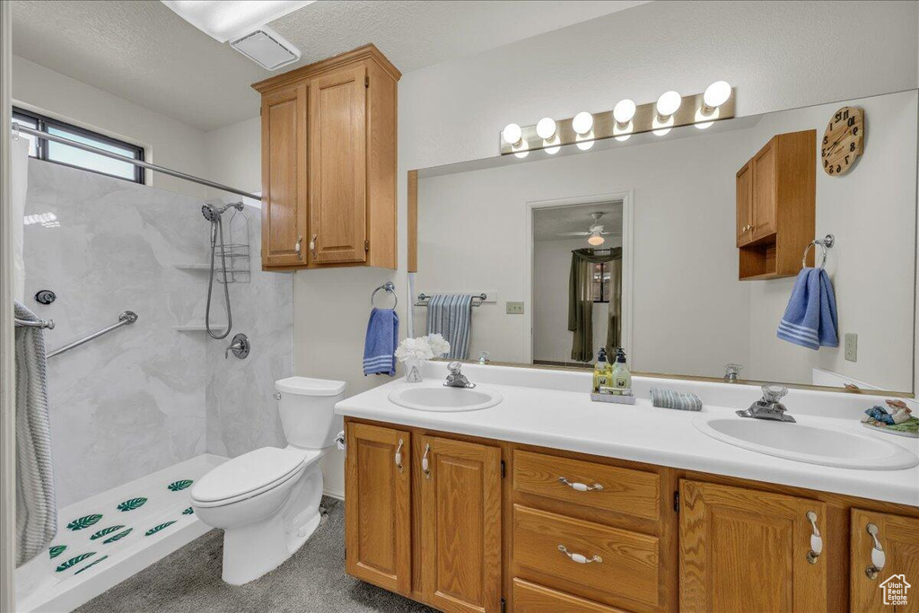 Bathroom featuring double vanity, a shower, and a ceiling fan