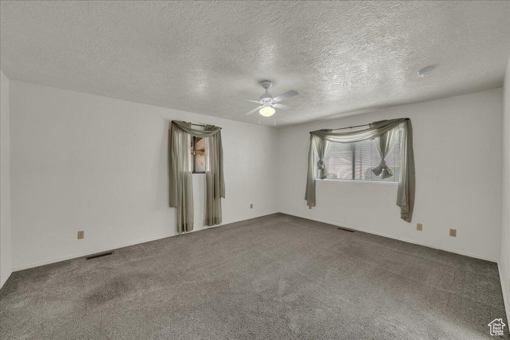 Empty room featuring a ceiling fan, carpet, a textured ceiling, and a smoke detector