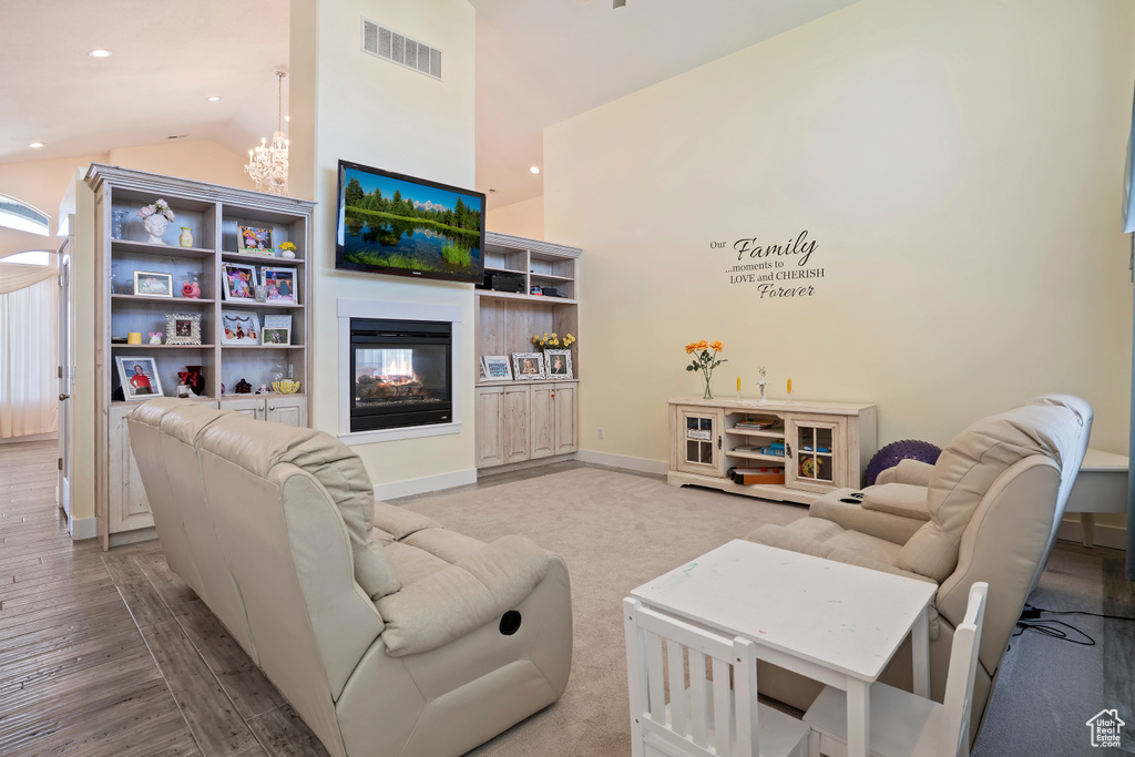Living room featuring a chandelier, high vaulted ceiling, wood finished floors, recessed lighting, and a multi sided fireplace
