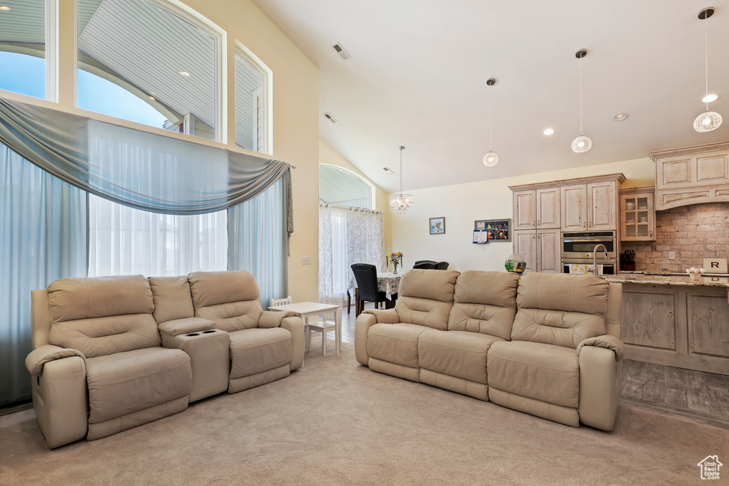 Living room featuring high vaulted ceiling, light carpet, a chandelier, and recessed lighting
