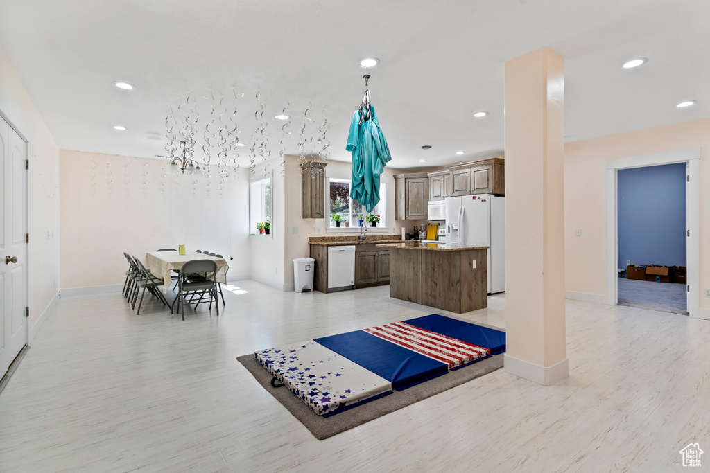 Kitchen with white appliances, a center island, recessed lighting, and light wood-style floors
