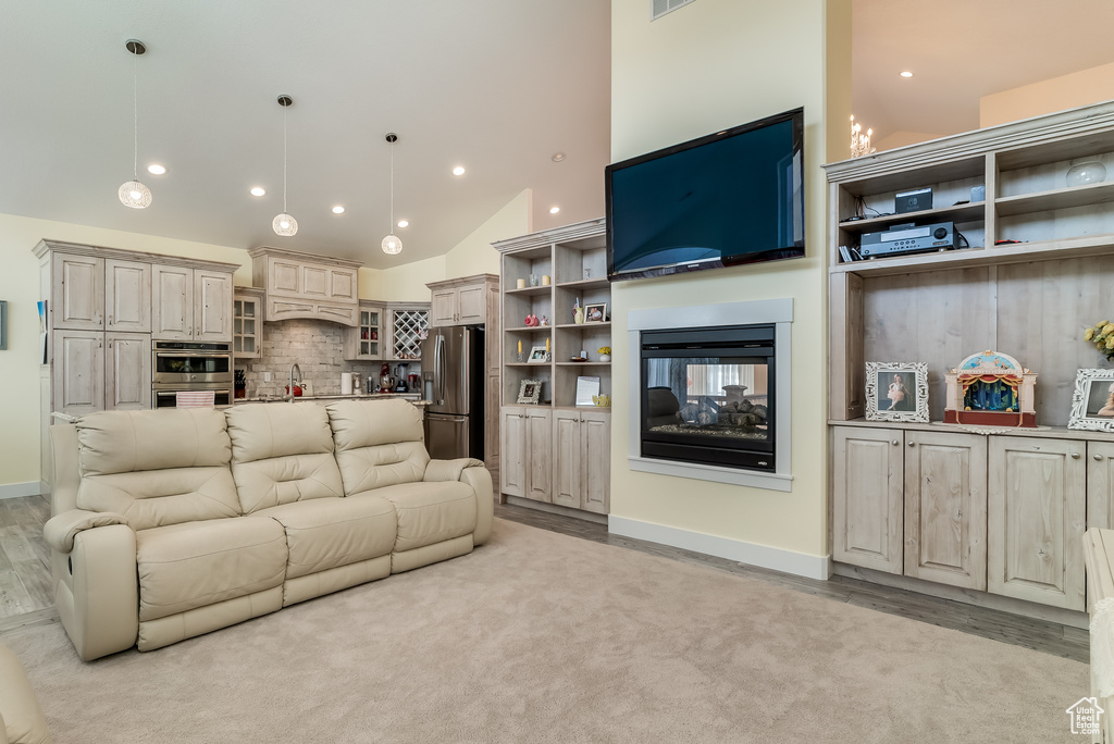 Living room featuring recessed lighting, light wood-style flooring, a multi sided fireplace, and high vaulted ceiling