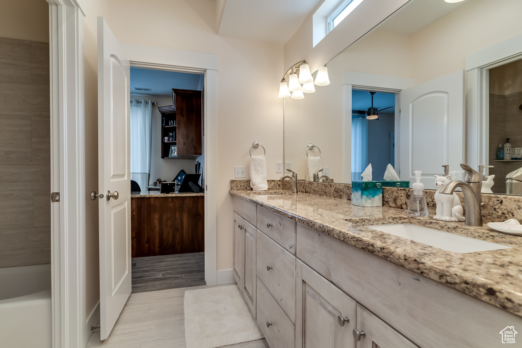 Bathroom with double vanity, a ceiling fan, and a tub to relax in