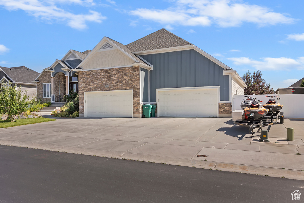 View of front of property featuring a garage, concrete driveway, board and batten siding, and stone siding