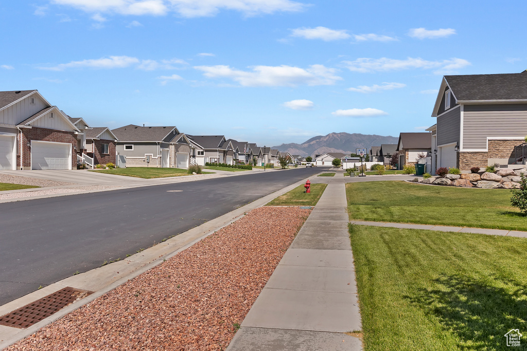 View of asphalt road with a residential view, sidewalks, and a mountain view
