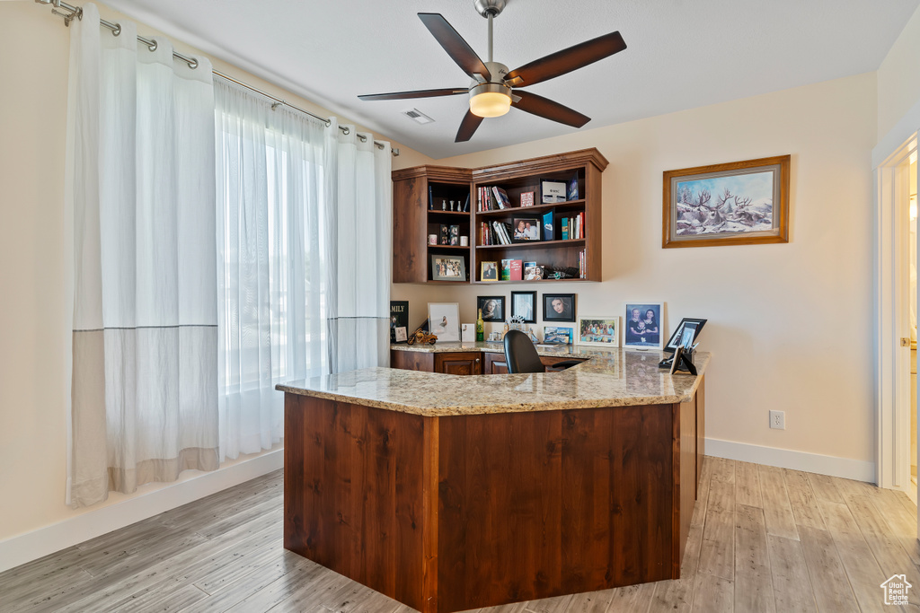 Office area with a ceiling fan, light wood-style flooring, and built in study area