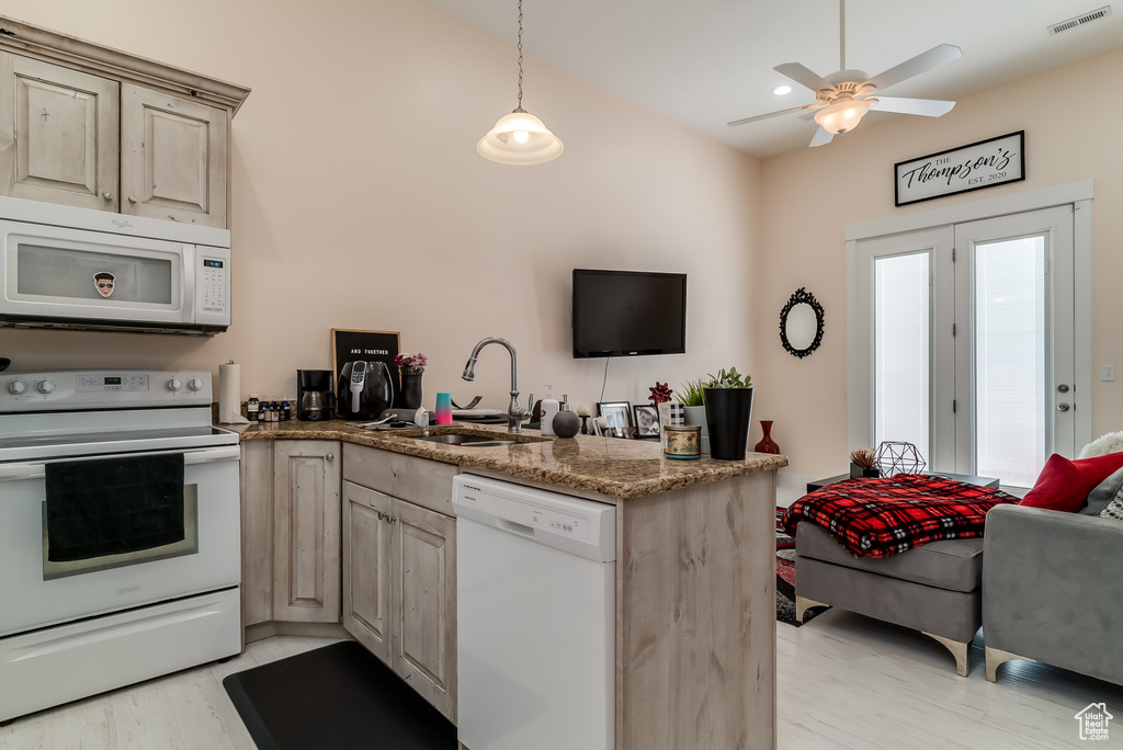 Kitchen with white appliances, a peninsula, a ceiling fan, light wood-style flooring, and decorative light fixtures
