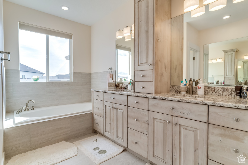 Bathroom with vanity, a garden tub, and tile patterned flooring
