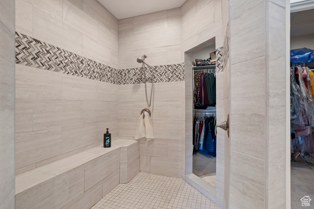 Full bathroom featuring a spacious closet, tiled shower, and tile patterned flooring
