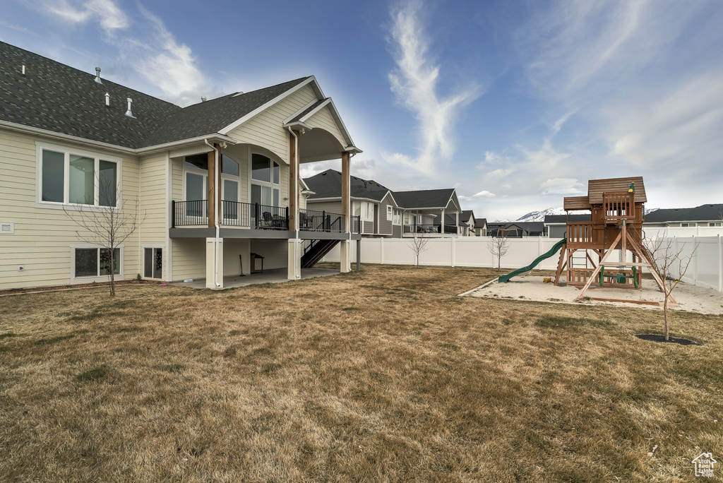 Fenced backyard with a playground, stairway, a patio, and a residential view